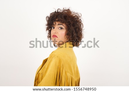 Beautiful woman with snobbish expression curving lips and raising eyebrows, looking with doubtful and skeptical expression, suspect and doubt. Standing indoors over gray background. Royalty-Free Stock Photo #1556748950