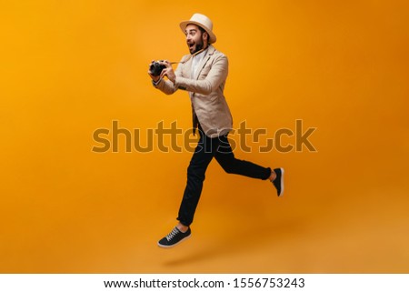 Happy man in stylish outfit jumping and taking photos