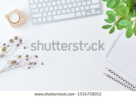 Blogger or freelancer workspace with keyboard, notebook and branches with green leaves on light background
