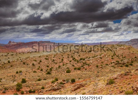 Rocky mountainsides under a cloudy sky in Arches National Park.
