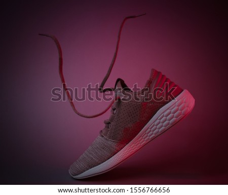 Running sports shoes with flying laces. Red neon light