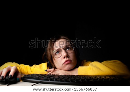young girl gamer sits at a laptop at night at home, a student plays games, she loses and wins