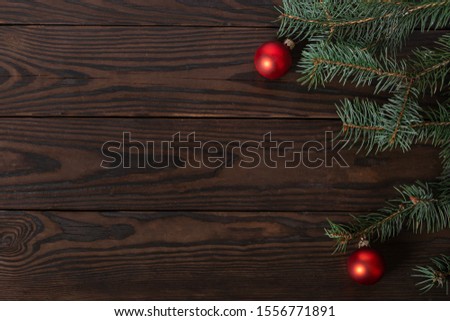 Christmas background with free space for text. Wooden textured background made of dark wood processed by fire. on the right is a Christmas tree branch with Christmas red balls Royalty-Free Stock Photo #1556771891