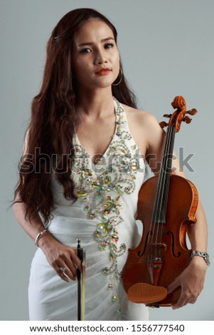 Southeast Asian violinist, Young beautiful Asian woman playing violin on gray background.