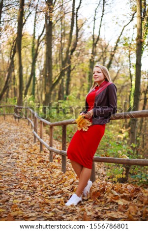 Happy young woman in a red dress carelessly having fun in a forest park enjoying nature