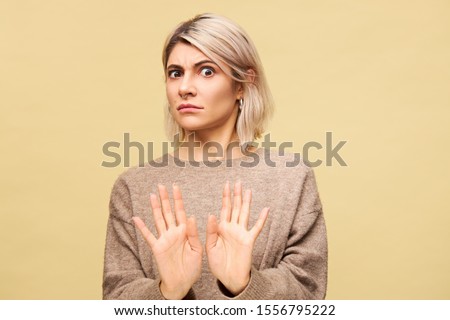 Portrait of outraged furious young European blonde woman expressing indignation, reaching out hands, making No or Stop gesture, saying Stay away from me while having fight with her boyfriend Royalty-Free Stock Photo #1556795222