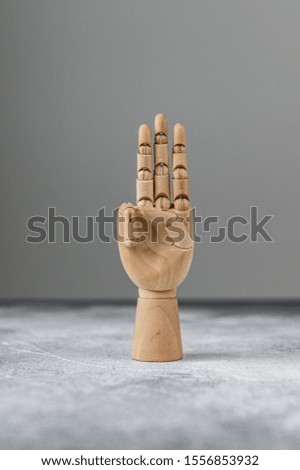 The wooden hand shows three raised fingers. The concept of communication