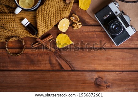 The concept of a cozy retro photo in autumn style, a sweater, a retro camera, a night light wooden star, vintage, a mug with hot tea, lemon and cinnamon, aroma oil in a cozy house. Against the backgro