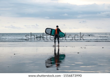A man enters the ocean for surfing