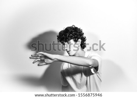 black and white portrait photography. handsome Italian expressive teenager model boy with curly hair posing and gesturing for a fashion shooting on white background