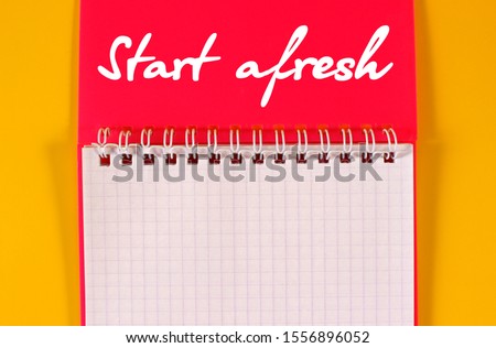 Open pink notebook on yellow background. Concept for new beginnings and planning in buisness / study, creativity and ideas. Slogan inviting to start afresh.