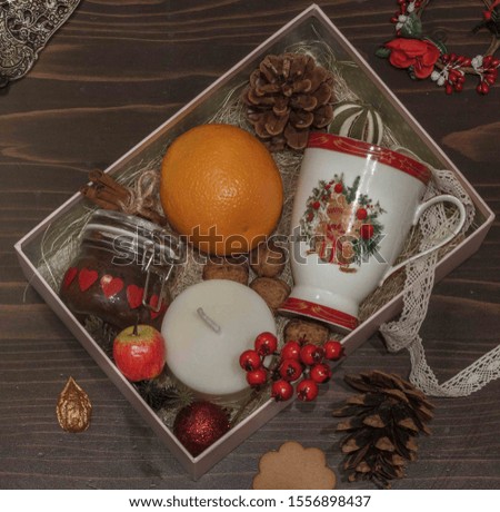 Christmas gift box with Cup, orange, candle, nuts and accessories