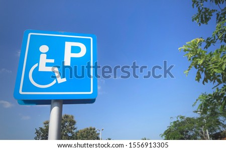 Blue parking for handicapped people sign with blue sky background.
