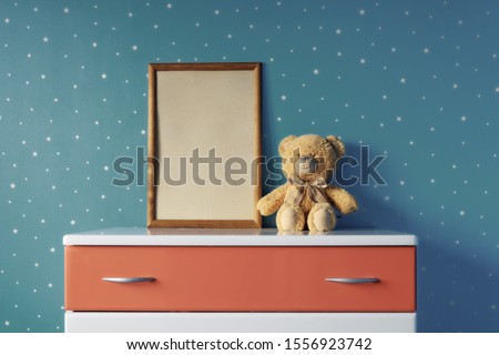 Children's room interior with dark blue star wall, photo frame, Teddy bear and dresser