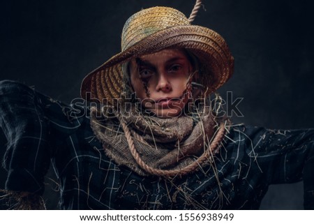 Portrait of young woman on masquerade in dreadful scarecrow costume on the dark background.