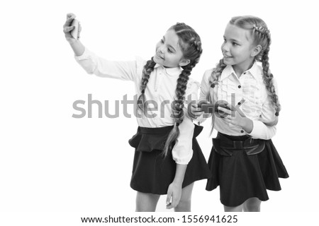 Nurturing your blog culture. Little schoolchildren making selfie for new blog isolated on white. Small bloggers keeping school life blog. Cute girls taking blog photos with smartphones, copy space.
