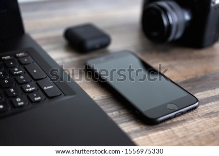 Photographer or stock photography concept, digital black camera near laptop and phone on desk workstation