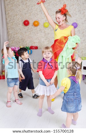 Four kids and holiday representative play game at children party.
