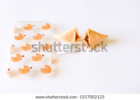 Fortune cookie with piece of paper on which is positive aphorism and phone case in this design on white background.