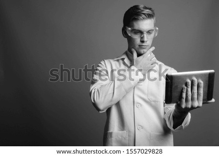 Portrait of young handsome man doctor as scientist in black and white