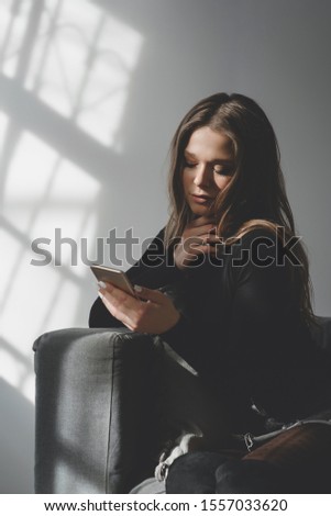 Portrait of a young sad crying girl with a smartphone in her hand, as a symbol of the negative impact of technology on the human psyche or unsuccessful relationships.