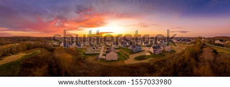 Aerial sunset panorama of luxury real estate development single family house neighborhood street with dramatic sky in Maryland USA