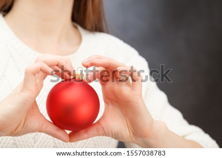 Female hands holding christmas red ball as a heart