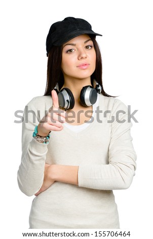 Teenager in black peaked cap thumbs up wearing earphones, isolated on white