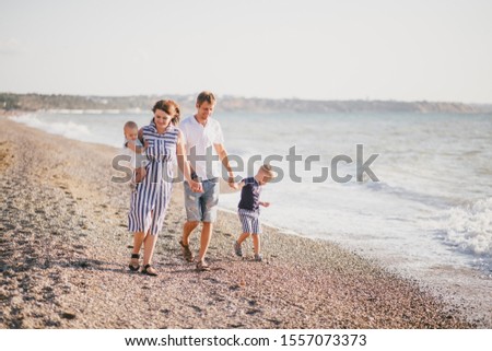 Happy family with two kids having fun near sea at the beach. 