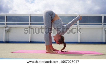 young beautiful girl in gray clothes practices yoga on a pink sack light background. Assana sports girl. yoga for health