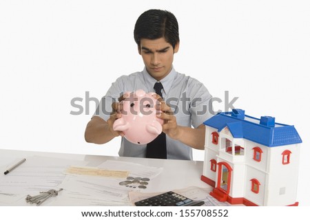 Real estate agent looking into piggy bank