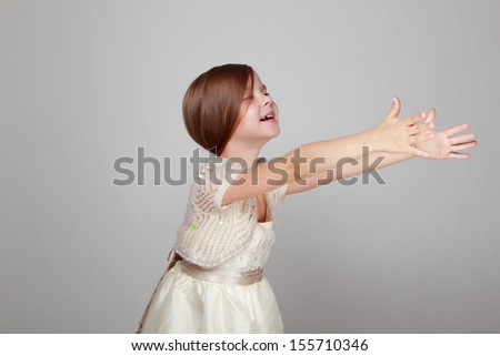 Adorable happy little girl with long hair in a fairy dress on a gray background on Holiday