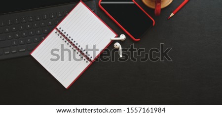 Top view of trendy workplace with notebook, laptop computer and office supplies on black table background 
