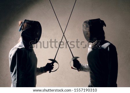 Fencer woman with fencing sword. Fencers duel concept. Royalty-Free Stock Photo #1557190310