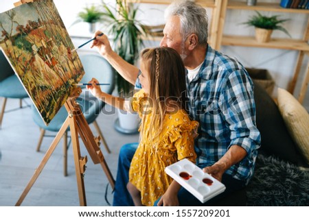 Senior man, grandfather and his grandchild drawing, painting together. Happy family time