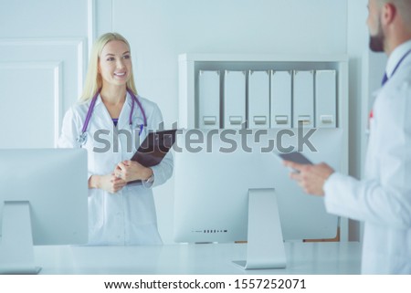 Female doctor standing with stethoscope at hospital looking at her male colleague