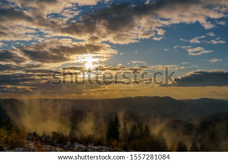 Sunset panorama in the Black Forest at golden hour with some fog and cloudy sky
