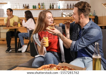 Young couple eating delicious pizza in cafe