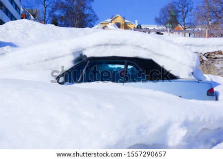 The car is completely covered with snow against the background of the city. Royalty-Free Stock Photo #1557290657