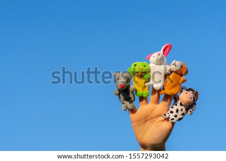 child hand with finger dolls: cow, frog, dog, rabbit, mouse, hare. animal finger puppets show and theater. Kid playing fingers puppets.