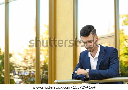 Portrait of handsome businessman looking at watch outdoors