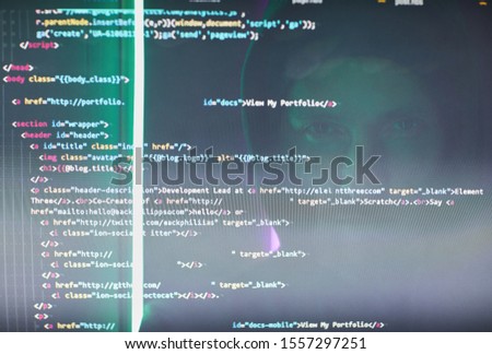 Close-up of computer monitor with codes and symbols and computer hacker reflecting on the monitor