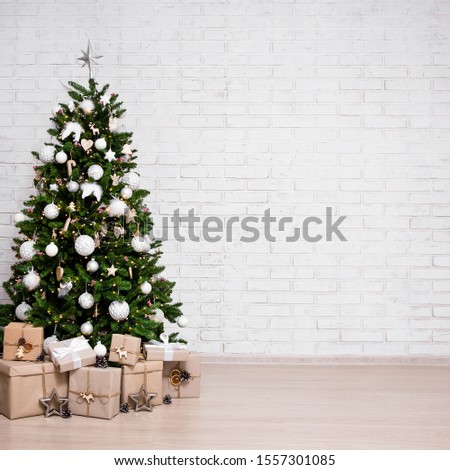 decorated christmas tree, heap of gift boxes over white brick wall background with copy space