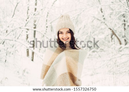 Girl rejoices the arrival of winter under a warm blanket in nature