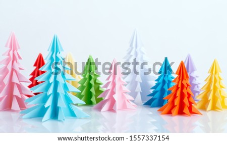 Shot of colorful Christmas trees with reflection made of origami. Banner or greeting card Merry Christmas or Happy New Year or a greeting winter, 