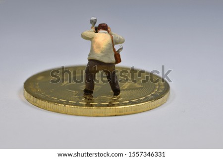 Mini figure is standing on a golden bitcoin taking a picture