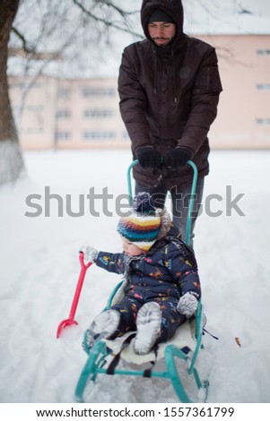 cute little boy playing with his father in snow park