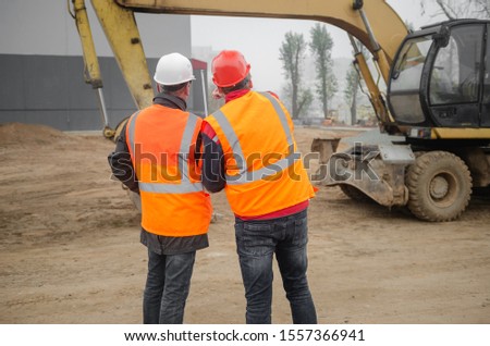 An engineer with a hard hat and helmet discussing a project at a construction site with a team leader. architecture construction concept. Industrial safety