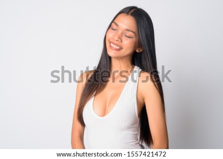 Portrait of happy young beautiful Asian woman relaxing with eyes closed