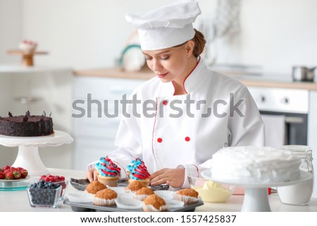 Female confectioner cooking tasty cupcakes in kitchen